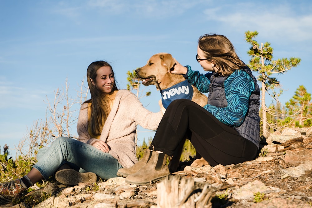 2 women sitting on rock during daytime