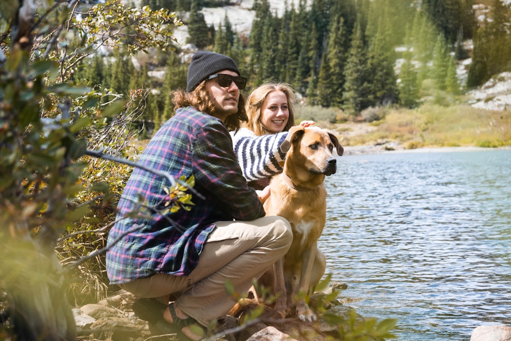 woman in purple and white striped long sleeve shirt sitting beside brown short coated dog