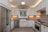 A modern kitchen features sleek stainless steel appliances, including a large refrigerator and oven. White cabinetry provides a clean and bright aesthetic, complemented by under-cabinet lighting. The subway tile backsplash and hexagonal floor tiles add texture and pattern, while the farmhouse sink is centered under a large window.