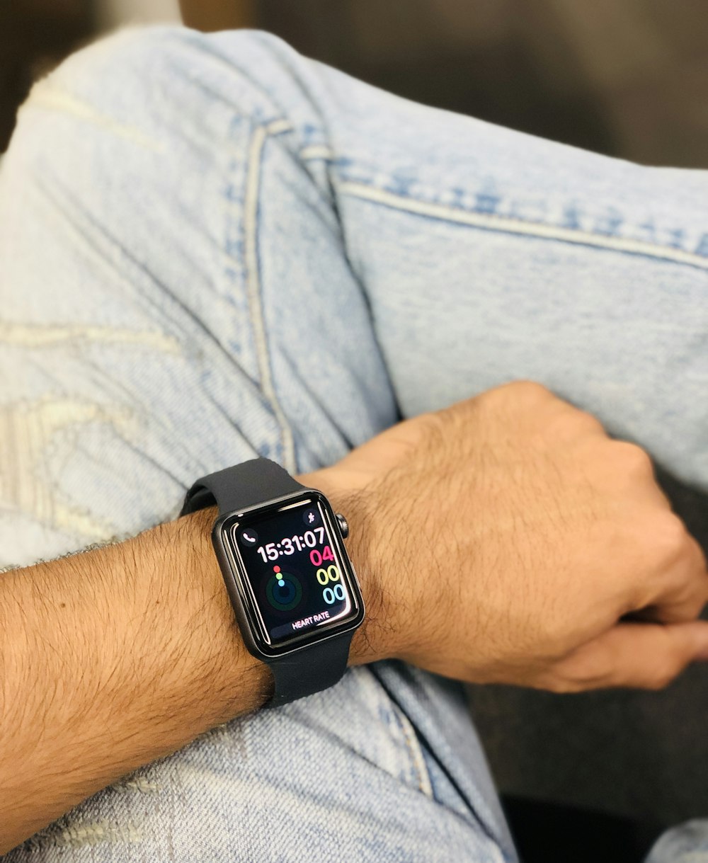 Persona che indossa una custodia in alluminio argentato Apple Watch con cinturino sportivo nero