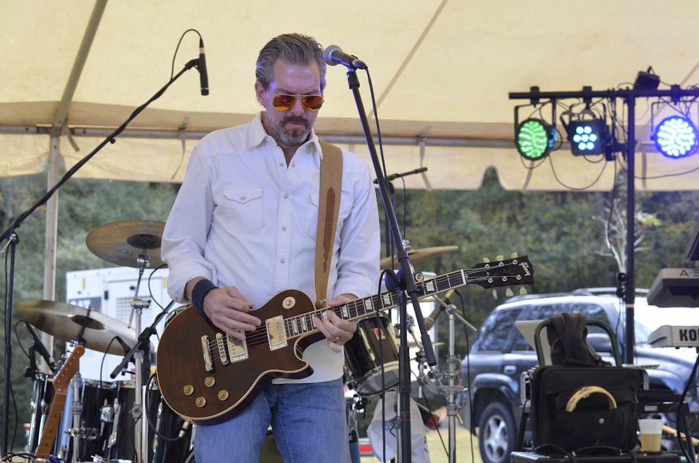 man in white dress shirt playing brown and black electric guitar