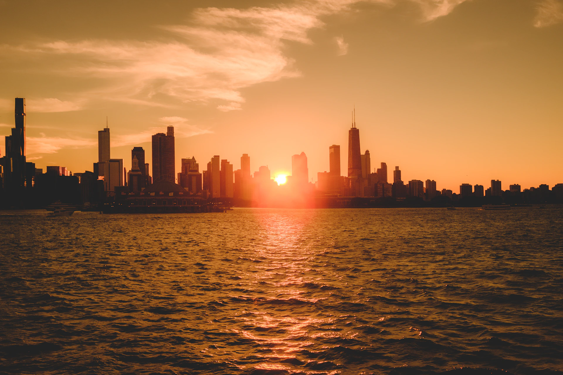 A cinematic still capturing a dramatic sunset over a city skyline, with warm golden hues reflecting off glass buildings.