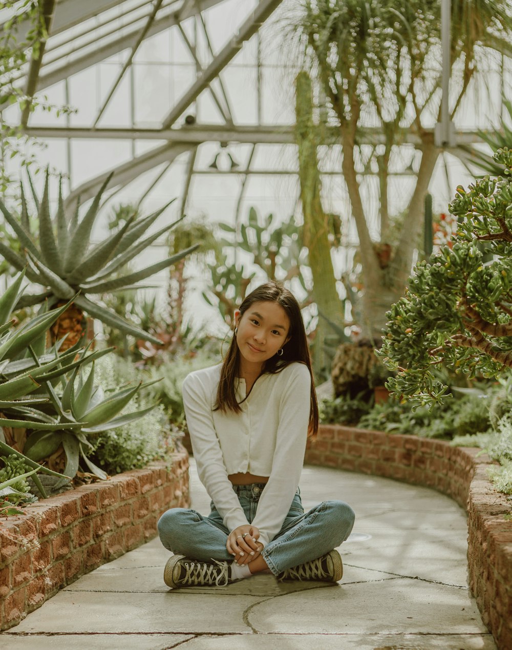 woman in white long sleeve shirt and blue denim jeans sitting on brown concrete bench