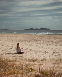 woman in red dress sitting on brown grass field during daytime