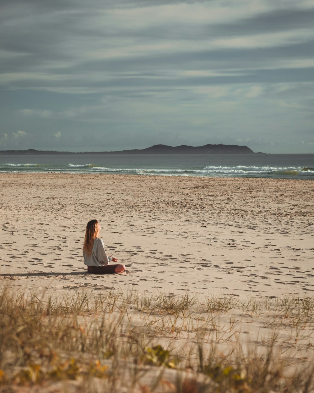 woman in red dress sitting on brown grass field during daytime