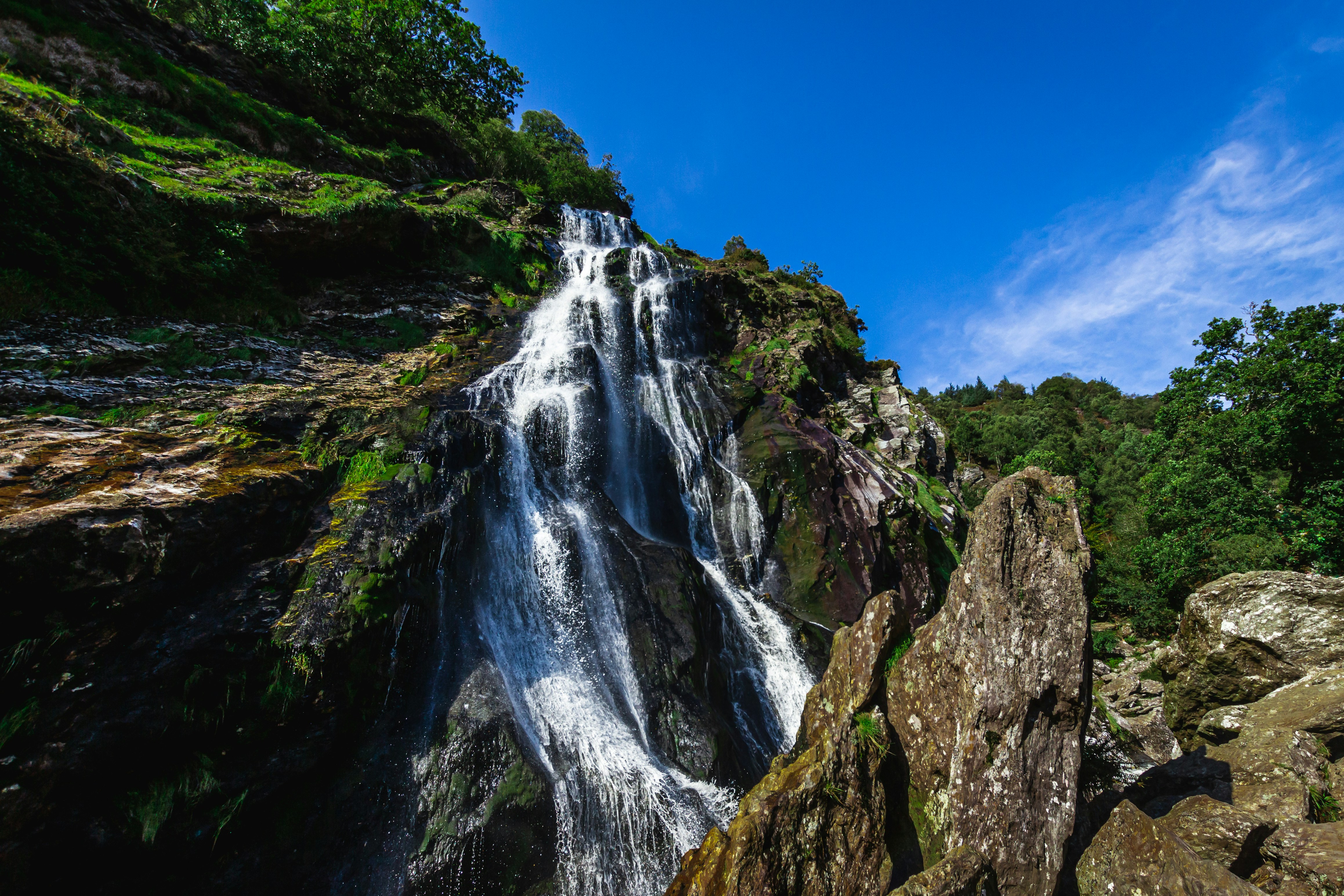 waterfalls on rocky mountain under blue sky during daytime