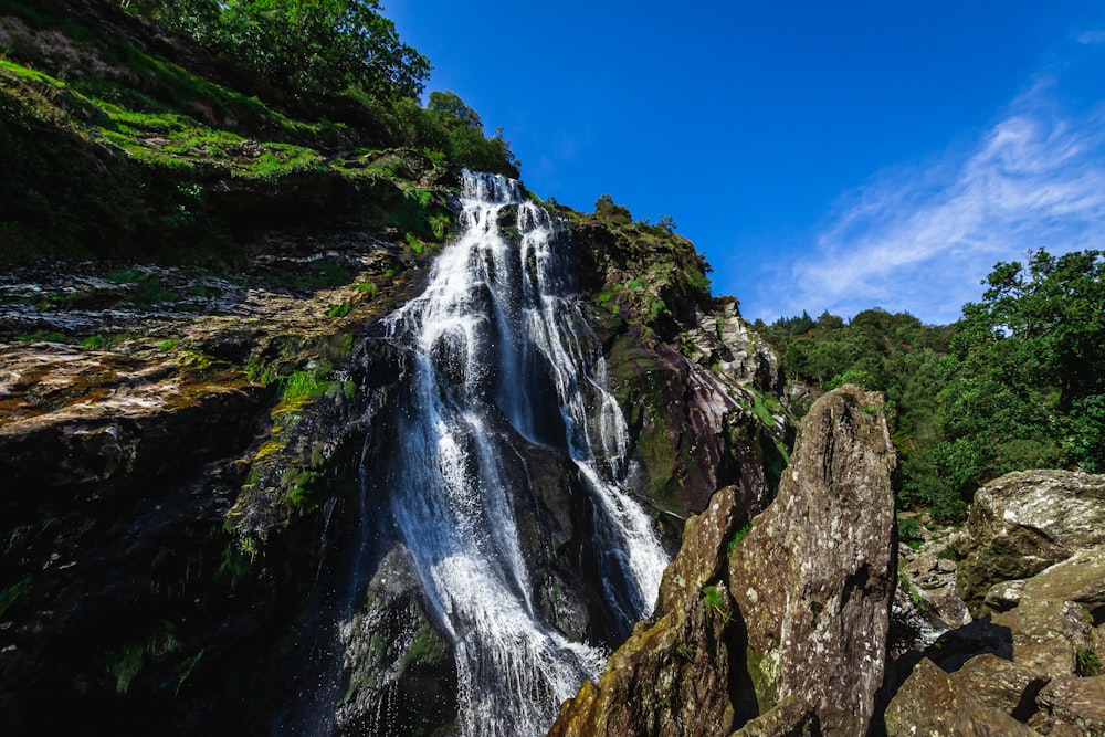 waterfalls on rocky mountain under blue sky during daytime