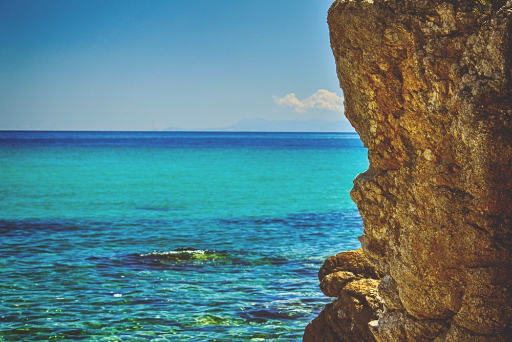 brown rock formation on blue sea under blue sky during daytime