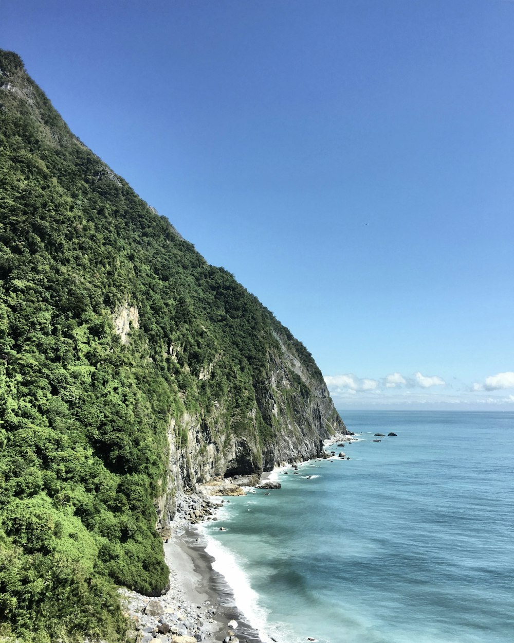 green and brown mountain beside body of water during daytime