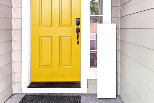 Wide shot of a freshly painted front door with new hardware in a sunny neighborhood.