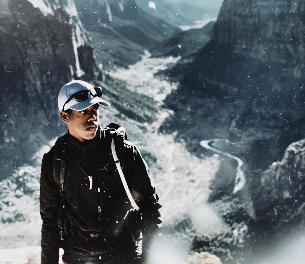 man in black jacket and black sunglasses standing on snow covered ground