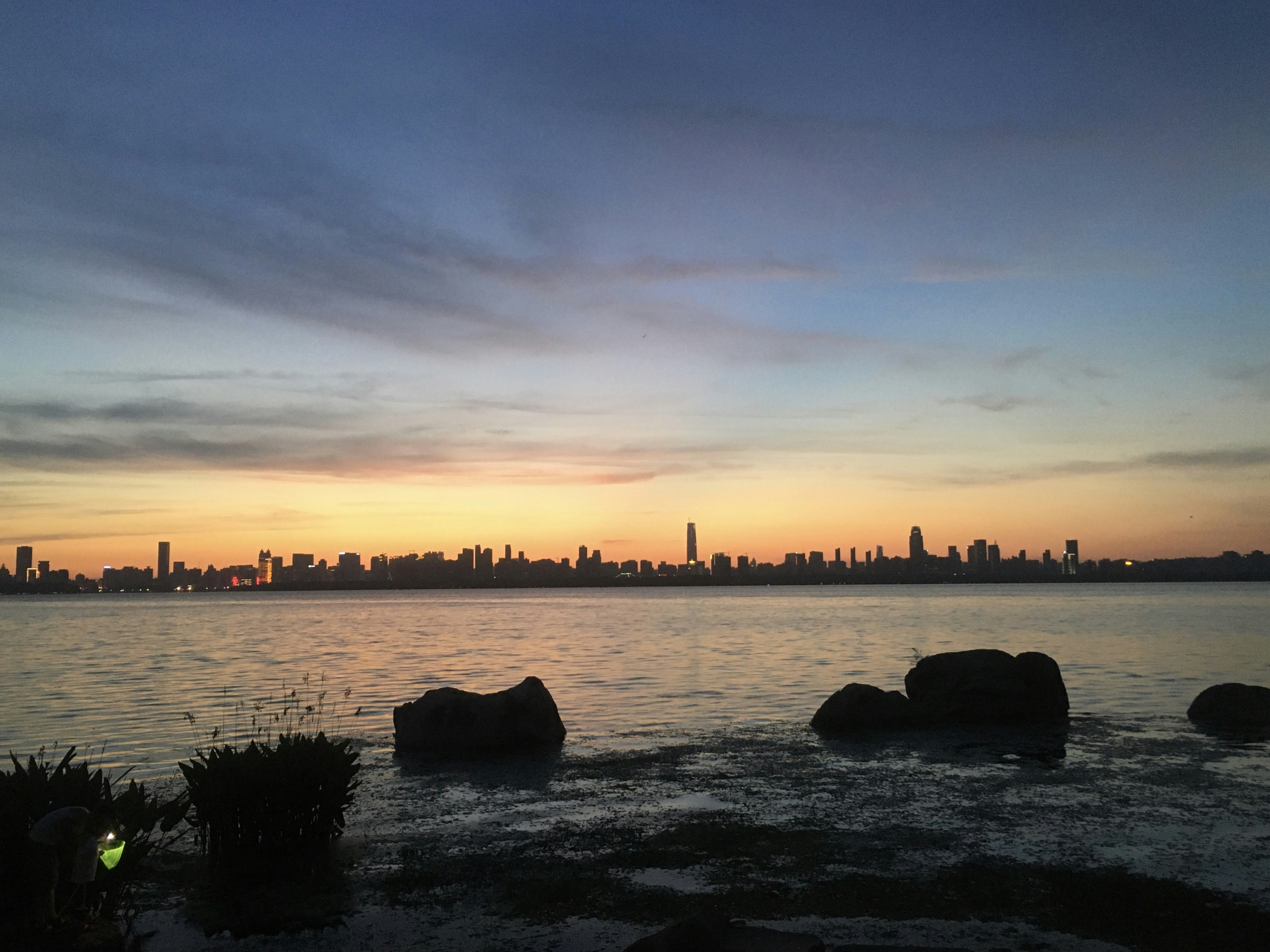 silhouette of rocks on water during sunset