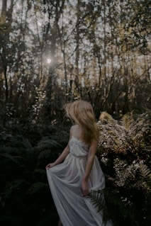 woman in white dress sitting on green grass during daytime