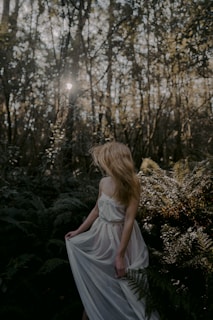 woman in white dress sitting on green grass during daytime