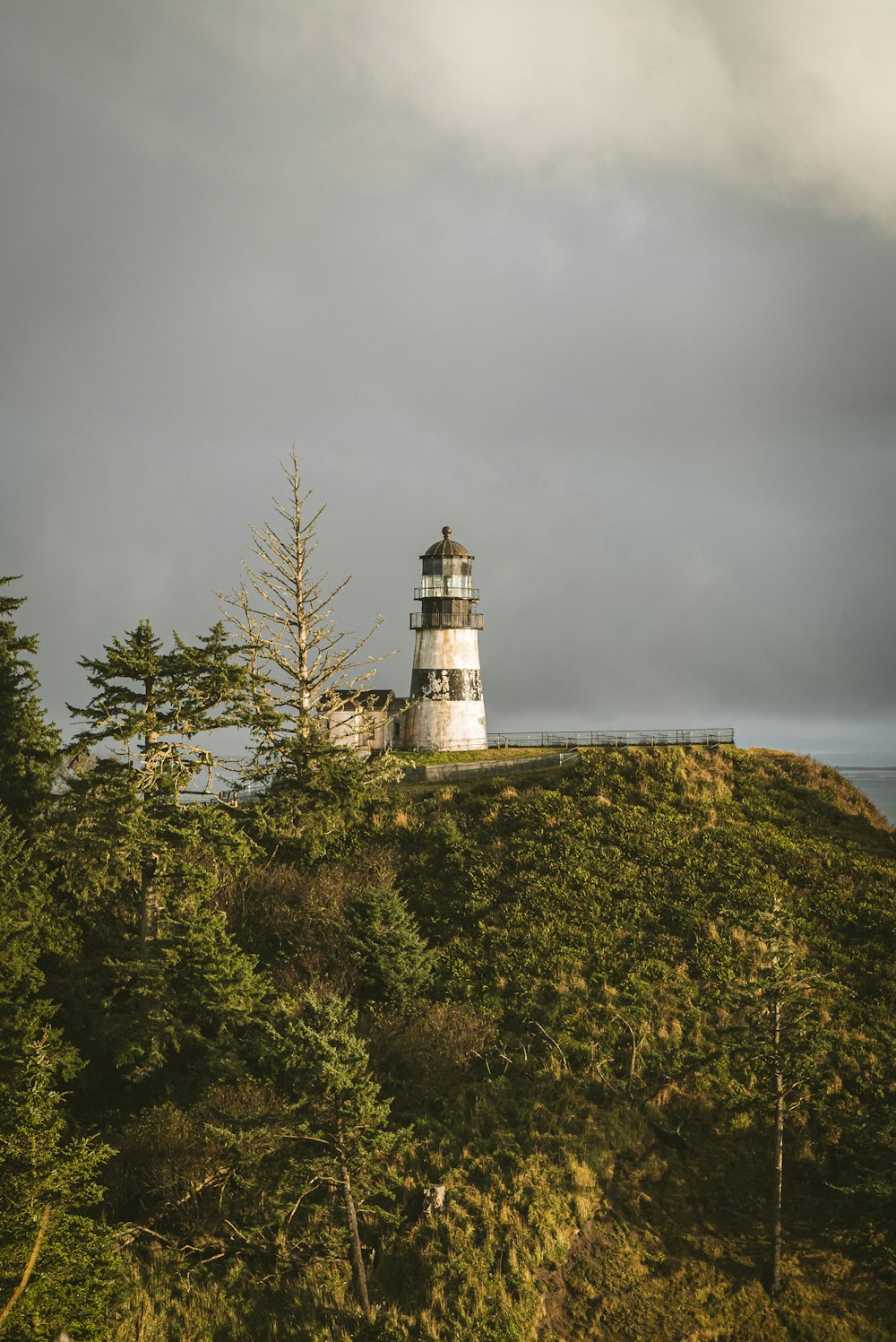 Phare blanc et noir sur un champ d’herbe verte sous un ciel nuageux gris