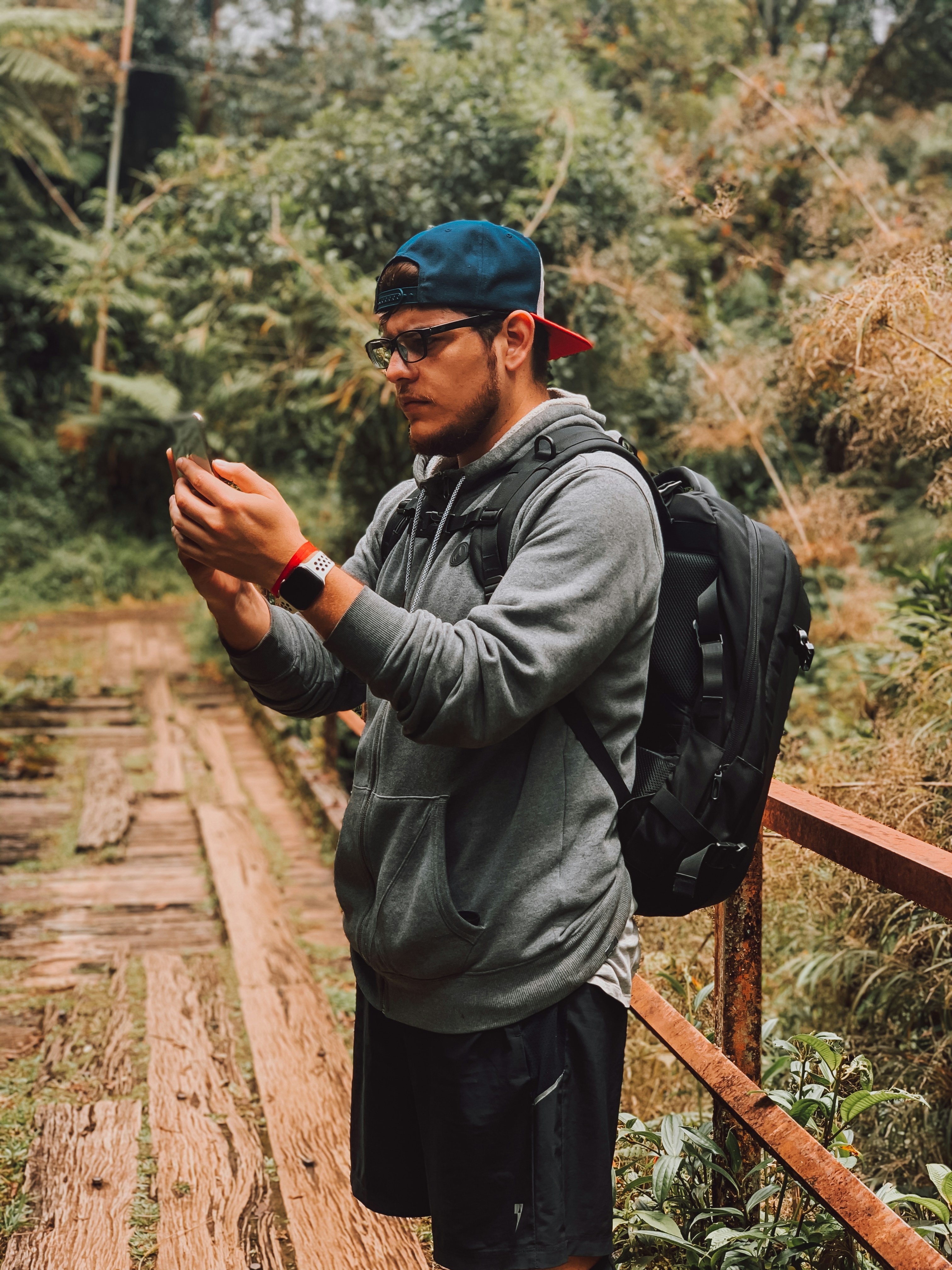 Pria berjaket abu-abu dan celana hitam memegang smartphone