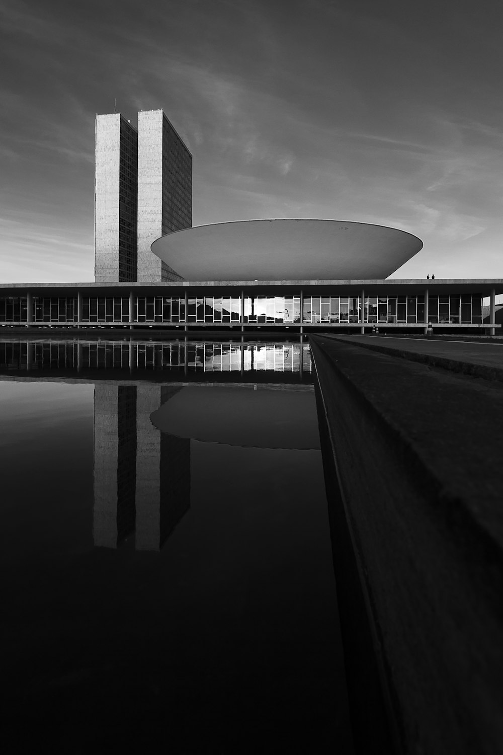 Foto en escala de grises de un edificio cerca de un cuerpo de agua