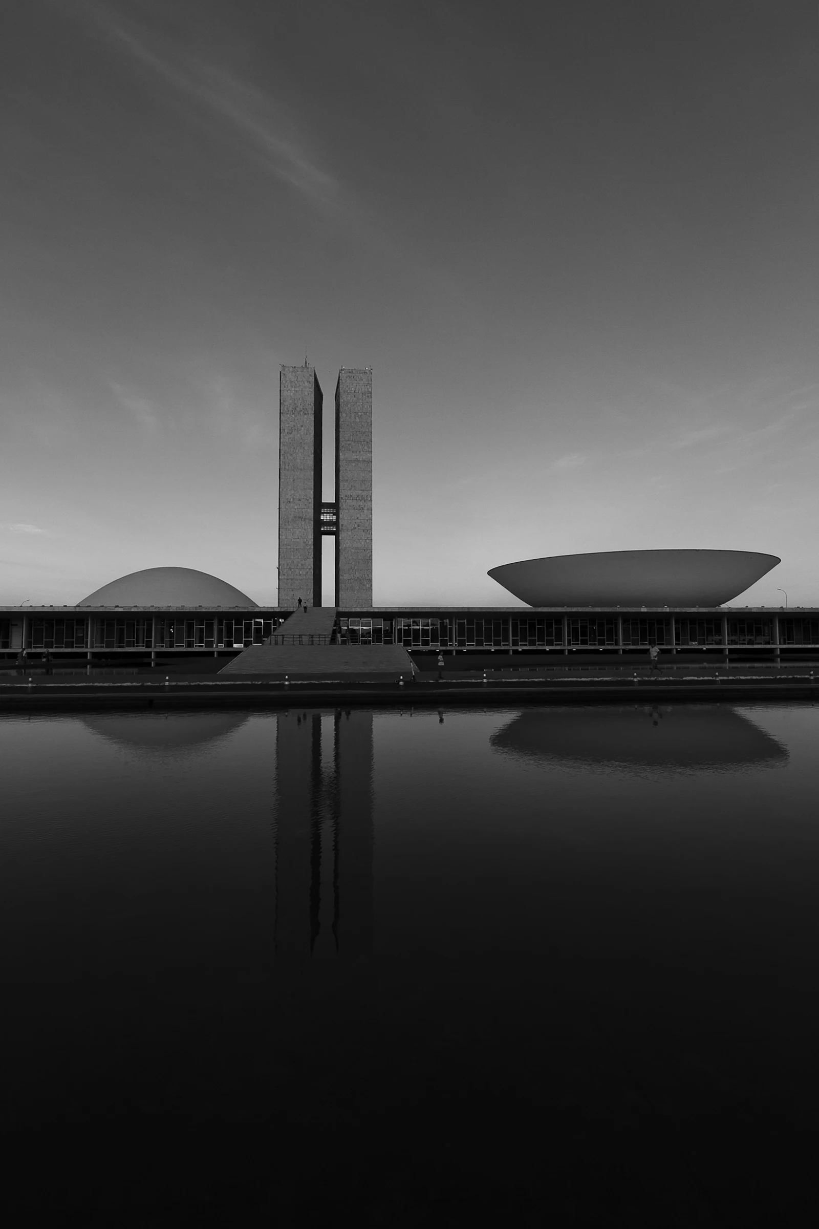 Congresso Nacional, em Brasília, com as torres e as cúpulas refletidas no espelho d’água.