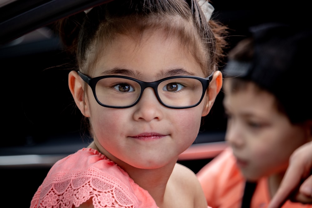 girl in pink sleeveless shirt wearing black framed eyeglasses