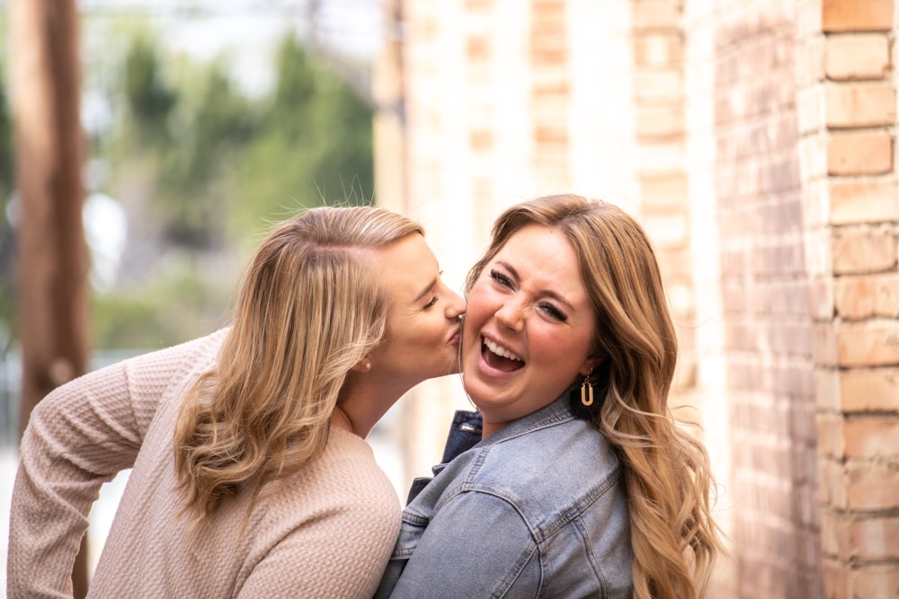 woman in gray coat kissing woman in brown sweater