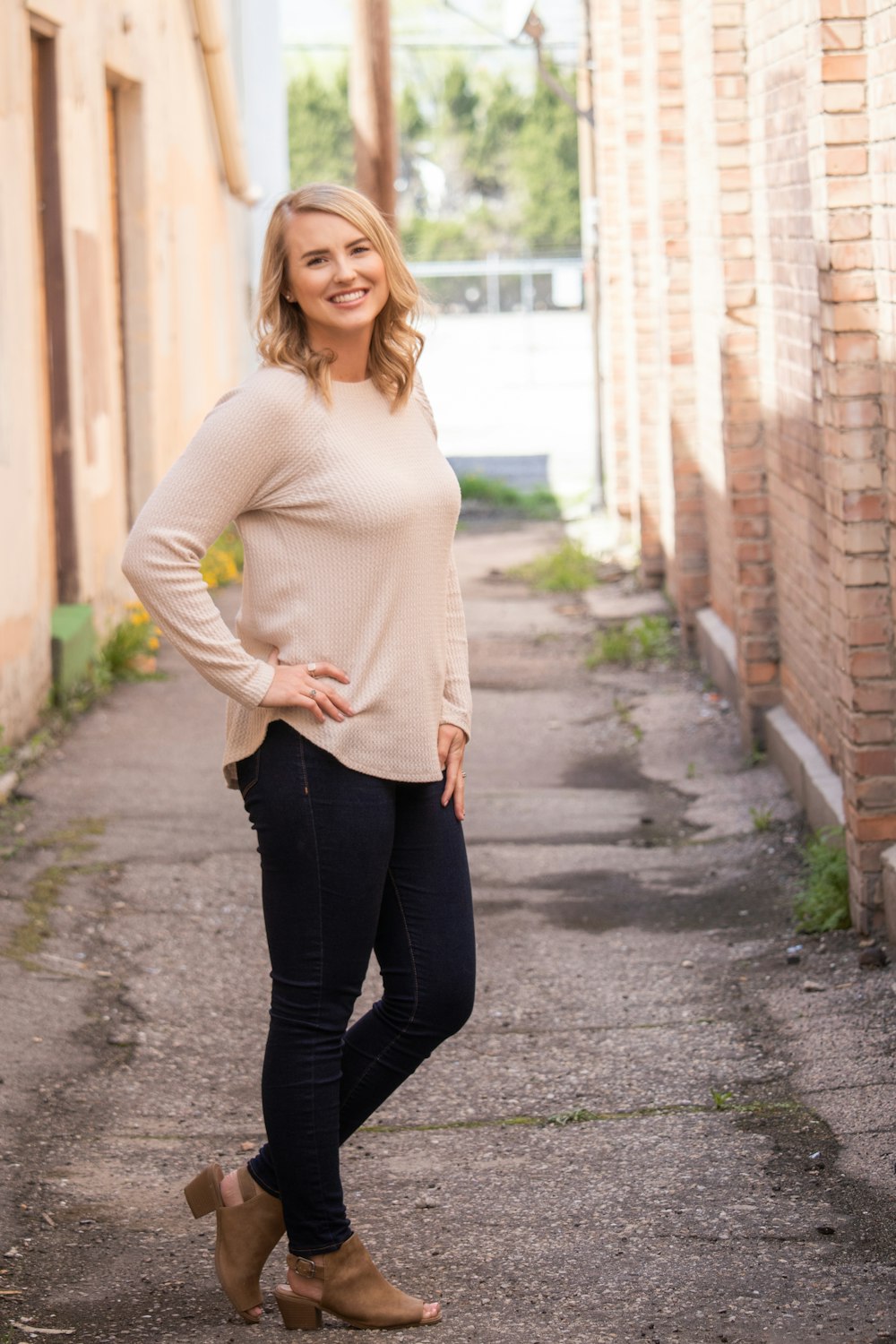 woman in white sweater and black pants standing on sidewalk during daytime