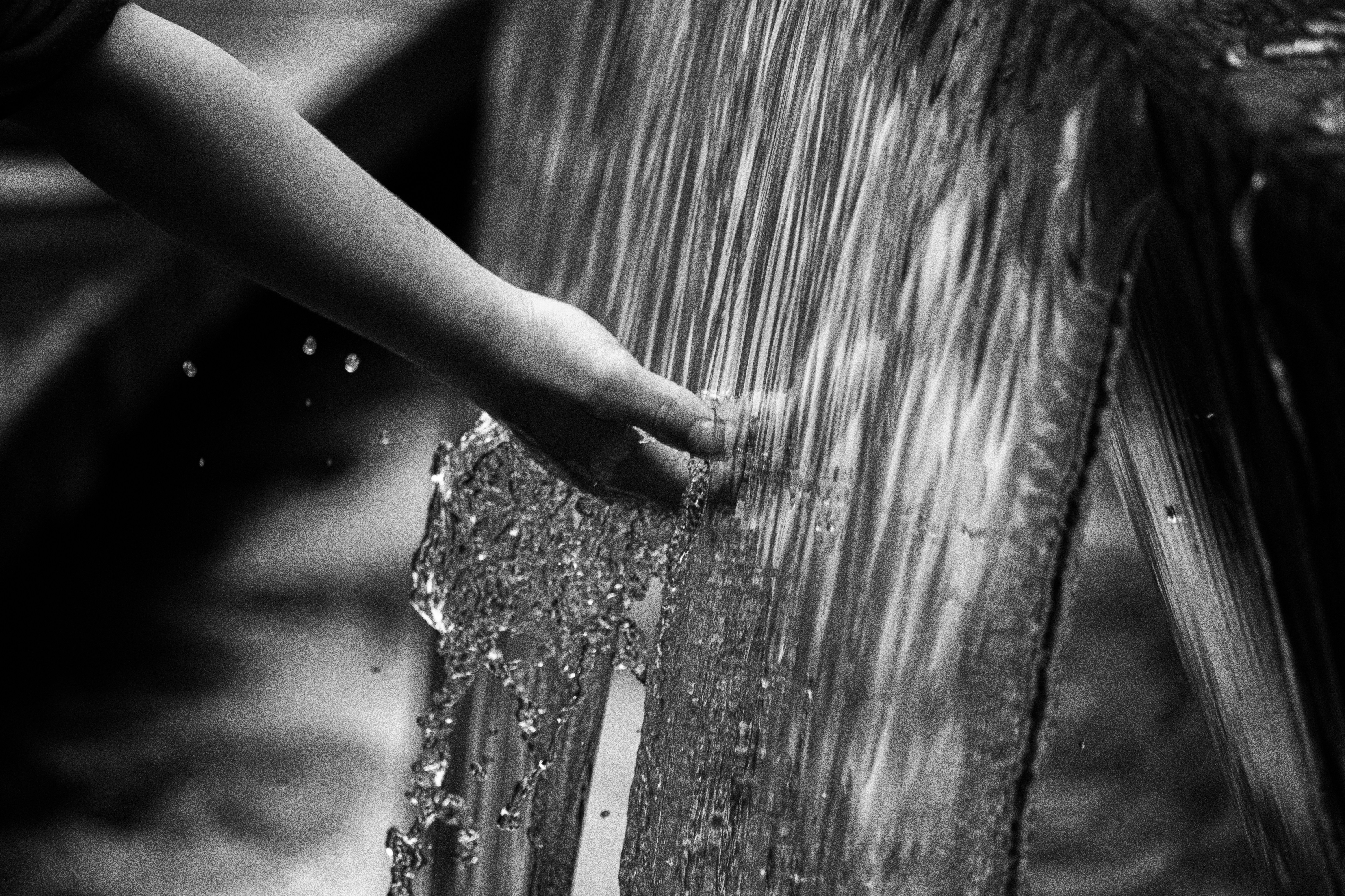 Grayscale photograph of a hand touching water, suggesting renewal and longevity