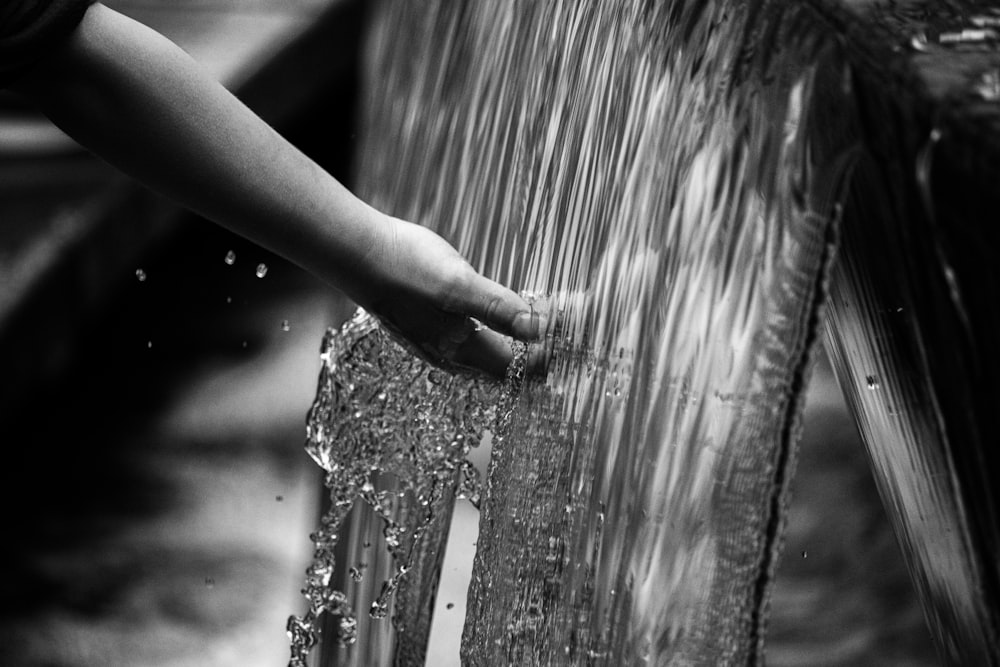 grayscale photo of persons hand on water