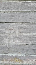 Weathered wooden boards with peeling paint and visible grain texture in a horizontal arrangement.