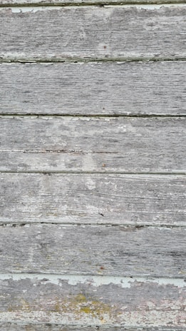Weathered wooden boards with peeling paint and visible grain texture in a horizontal arrangement.
