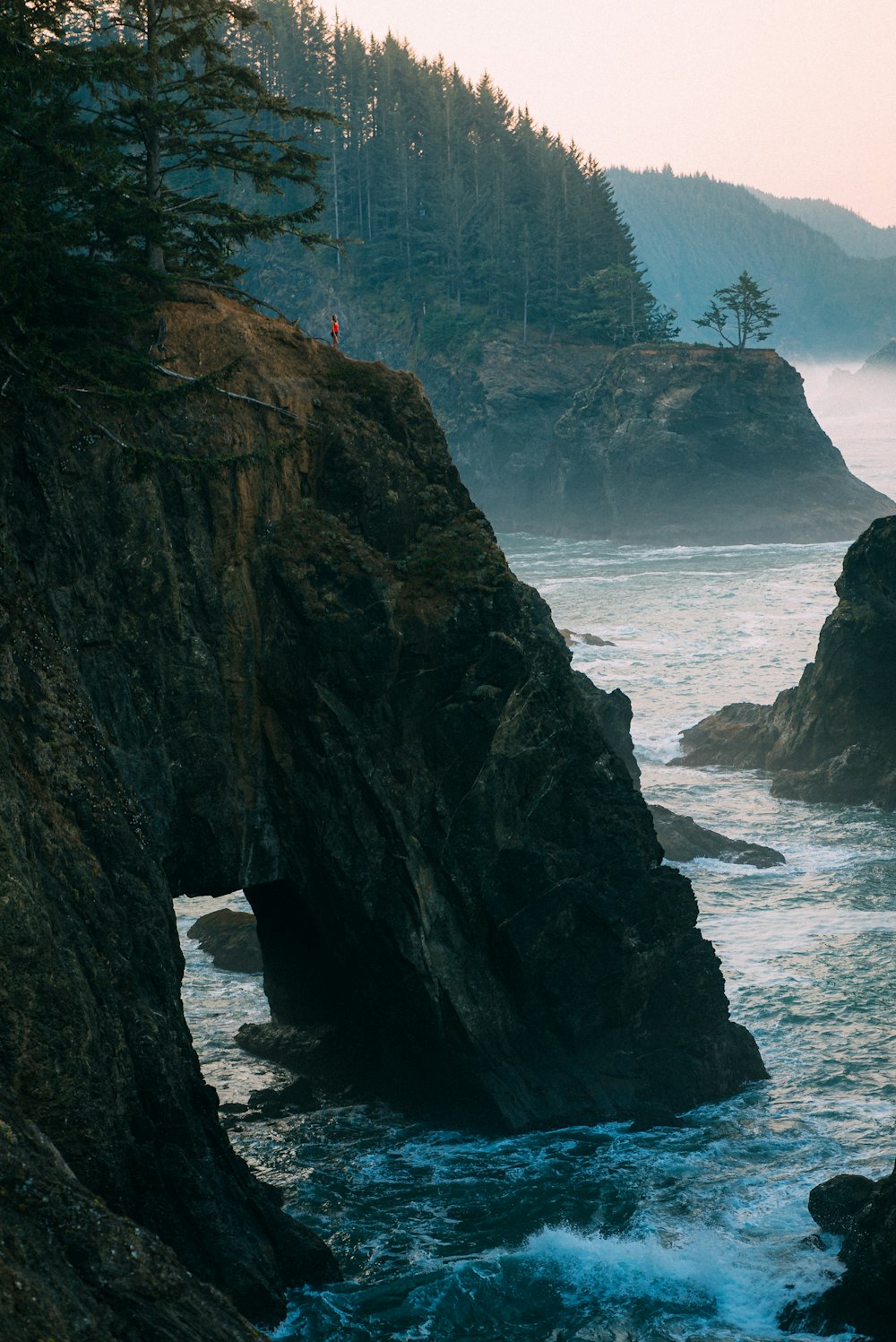 black rock formation on body of water during daytime