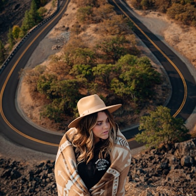 woman in brown hat and brown jacket standing on road during daytime