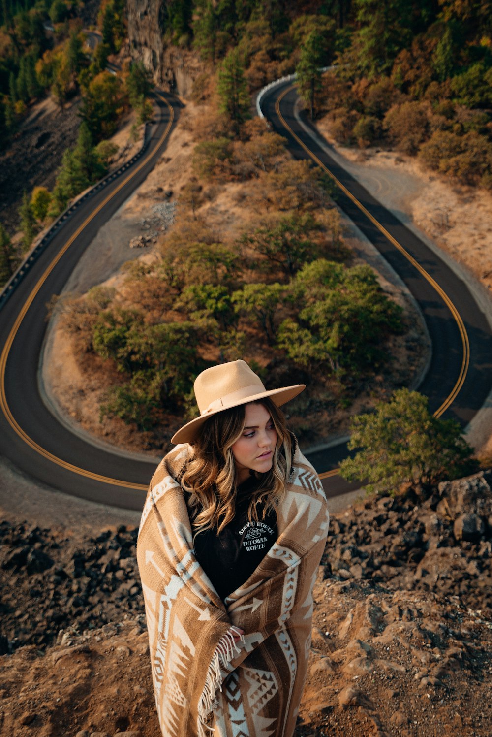 갈색 모자와 갈색 재킷을 입은 여자가 낮에 도로에 서 있다