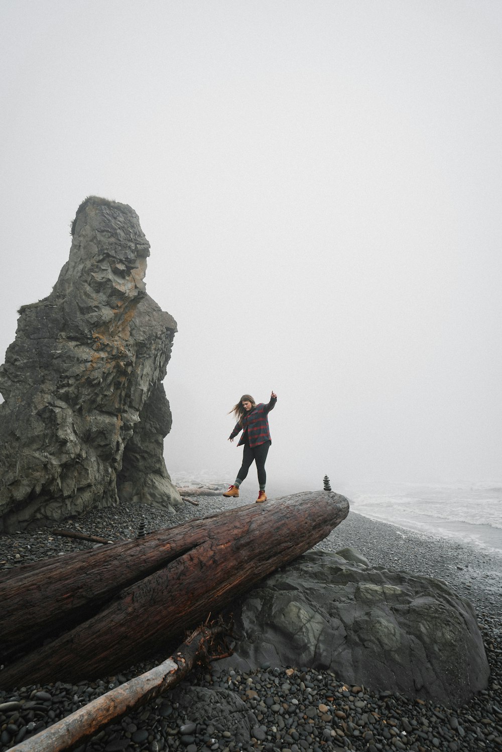 woman in black jacket and black pants standing on brown rock formation during daytime