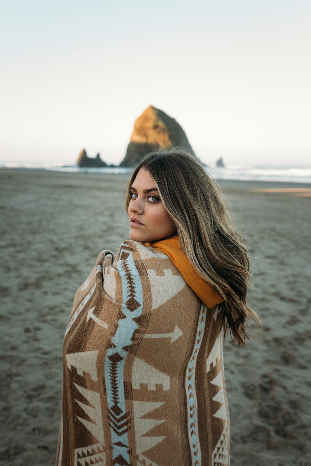 woman in brown and white scarf standing on beach during daytime