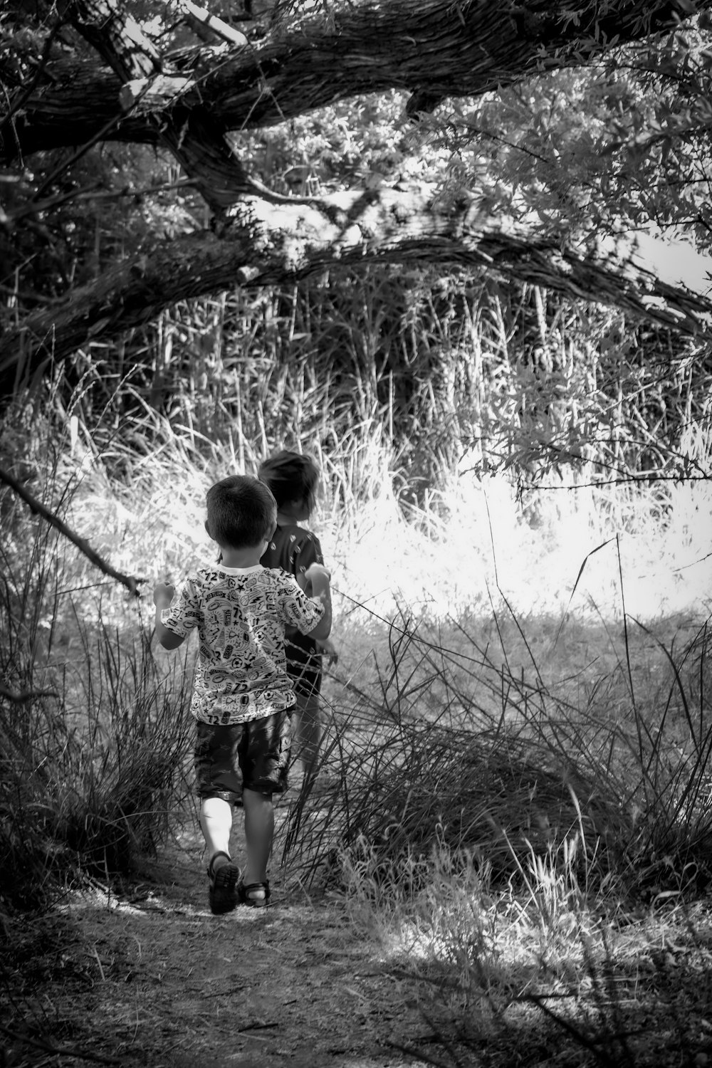 grayscale photo of child standing on grass field