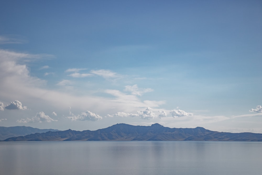 white clouds over snow covered mountains and lake