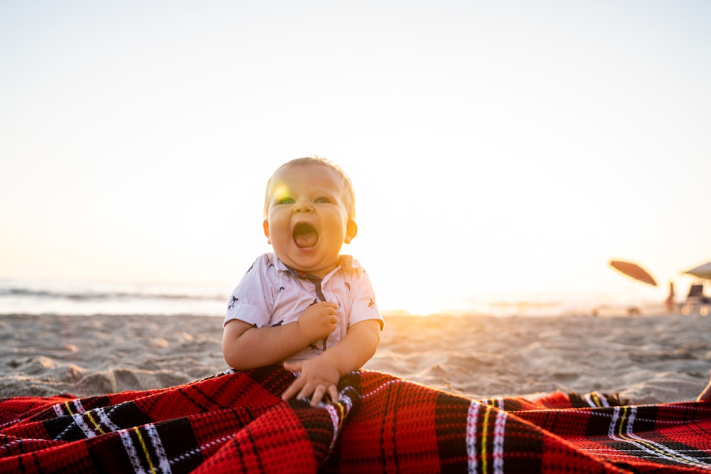 boy in blue polo shirt sitting on red and black plaid textile