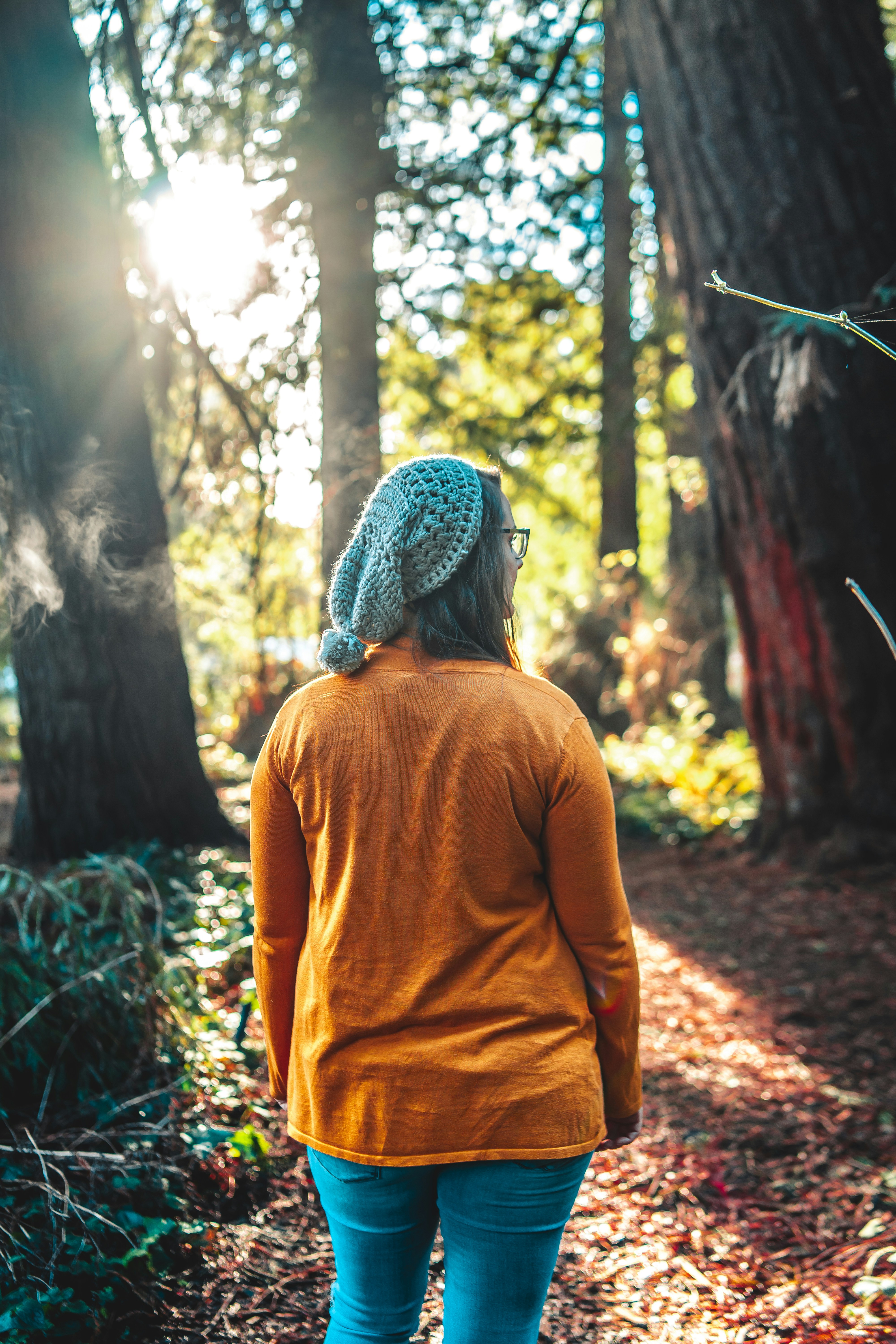 woman in yellow long sleeve shirt and gray knit cap standing in forest during daytime