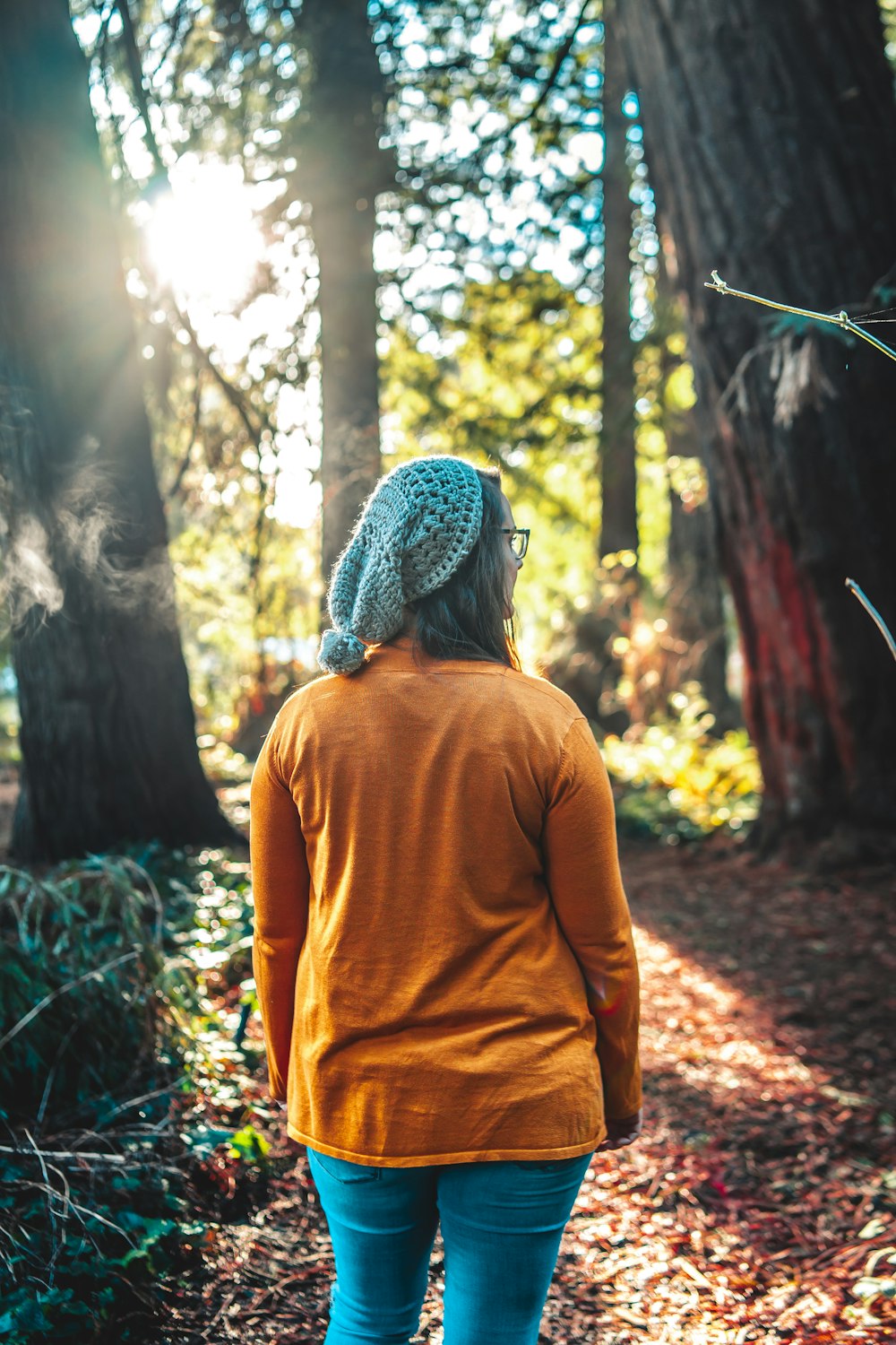 woman in yellow long sleeve shirt and gray knit cap standing in forest during daytime