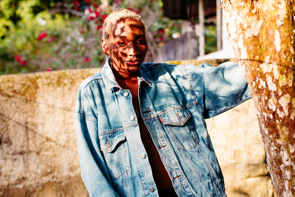 man in blue denim jacket standing near brown wall during daytime