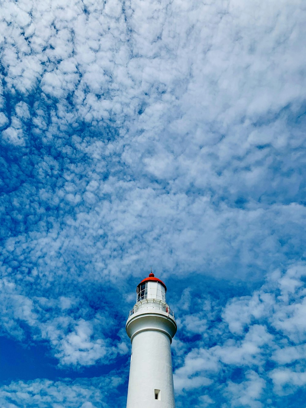 white and red lighthouse under blue sky and white clouds during daytime