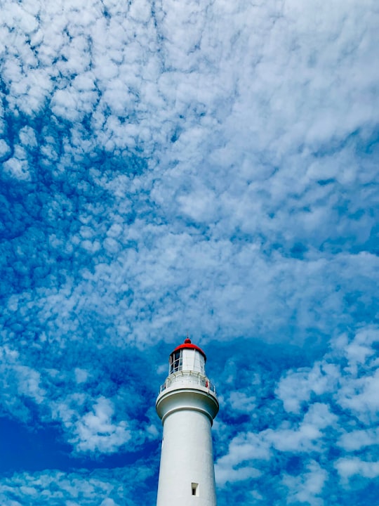 white and red lighthouse under blue sky and white clouds during daytime in Aireys Inlet VIC Australia