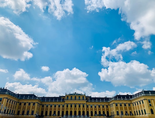 yellow concrete building under blue sky and white clouds during daytime in Schönbrunn Palace Austria