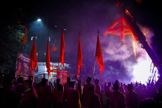A vibrant crowd at a Kerala political rally waving flags with red and gold hues under dramatic lighting.