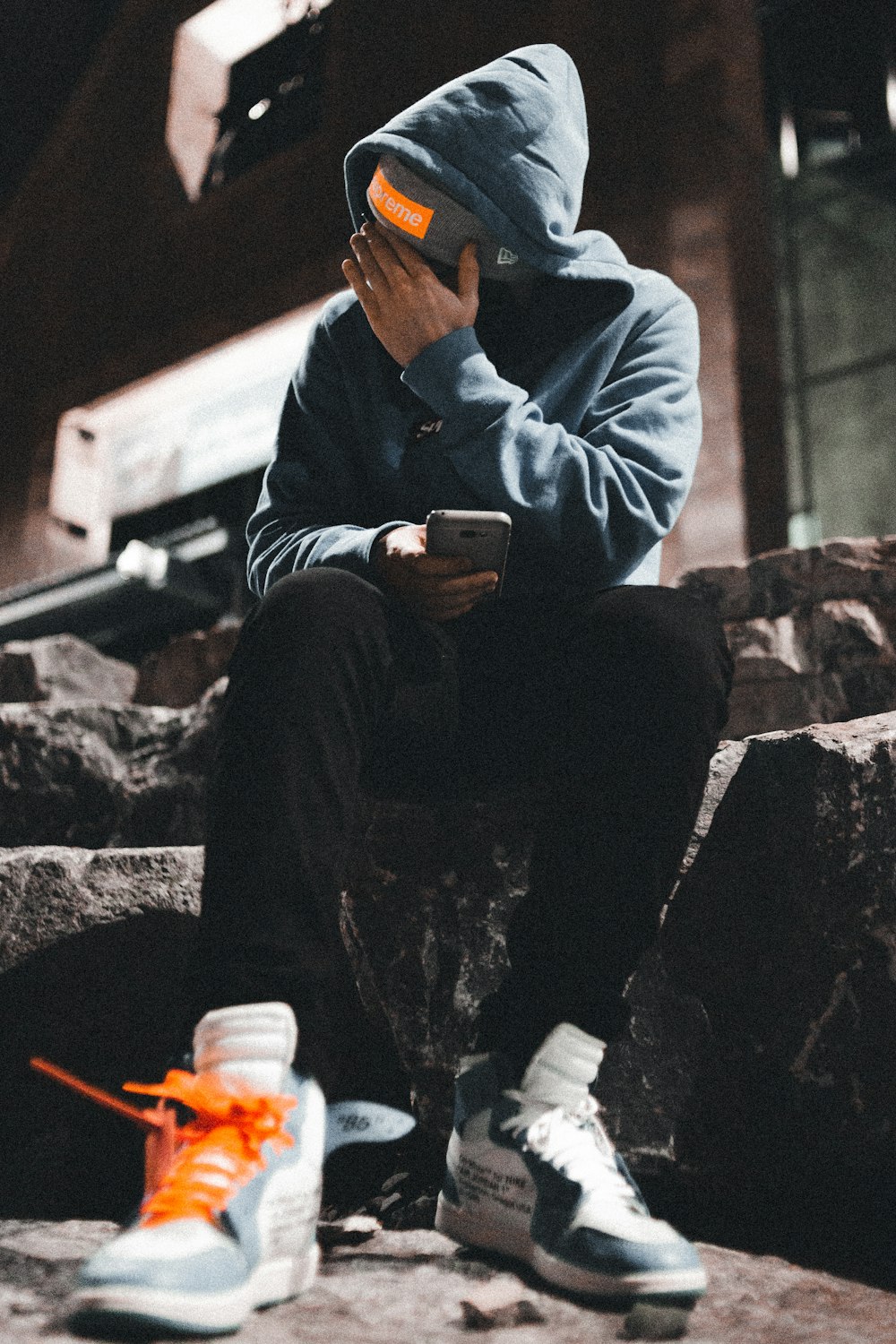 man in gray hoodie sitting on gray concrete bench