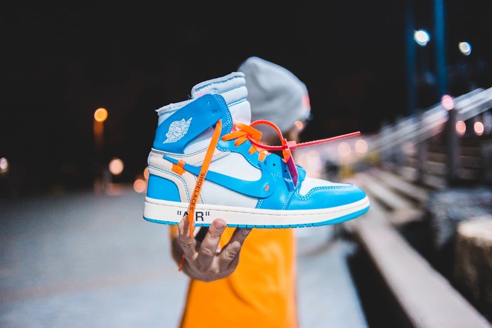 person holding blue and white nike air jordan 1 shoe