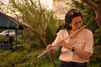 woman in white shirt playing flute flute google meet background