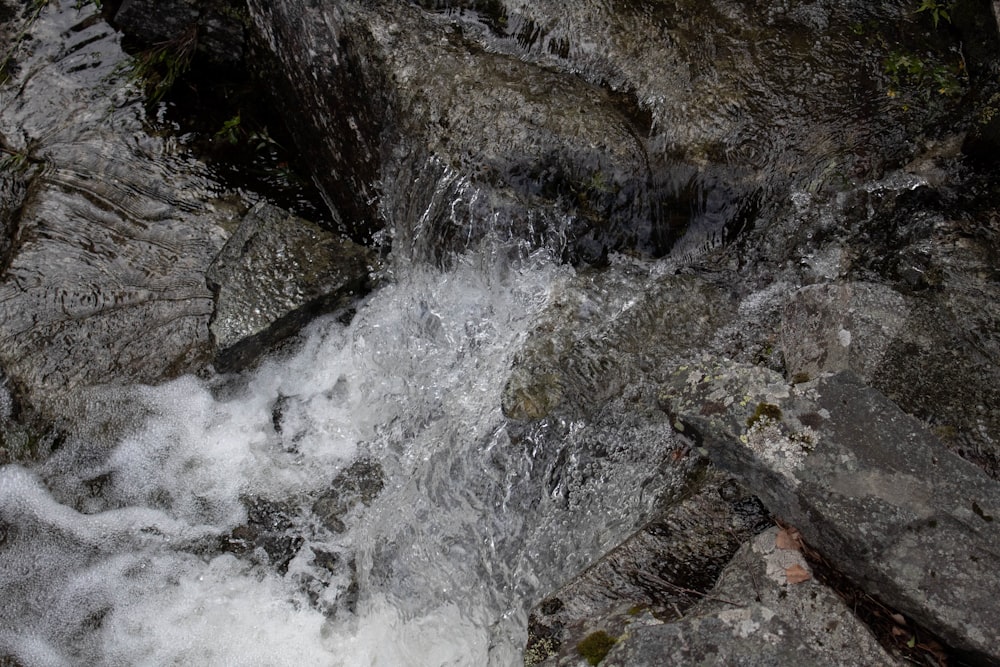 water falls on rocky shore during daytime