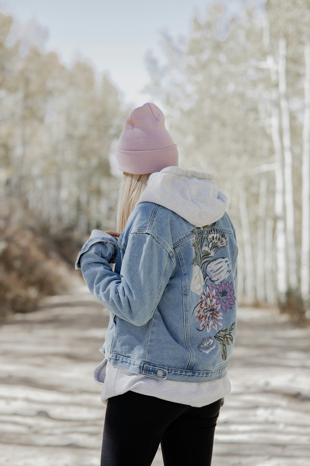 girl in pink knit cap and blue denim jacket standing on snow covered ground during daytime