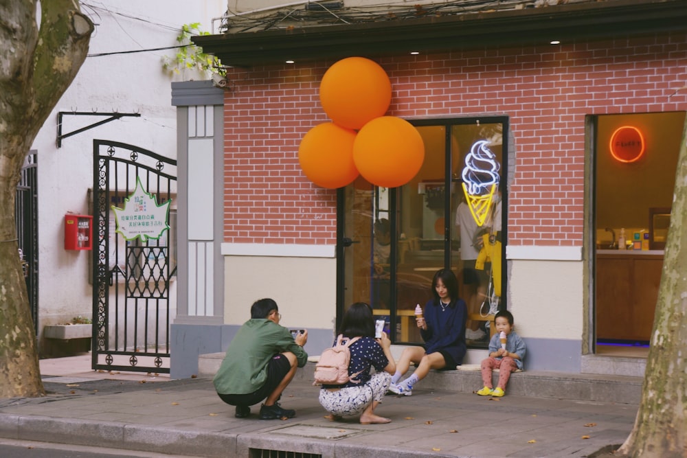 people sitting on bench near orange balloons during daytime
